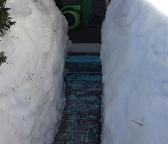 A home with tall snow banks on either side of the walk way